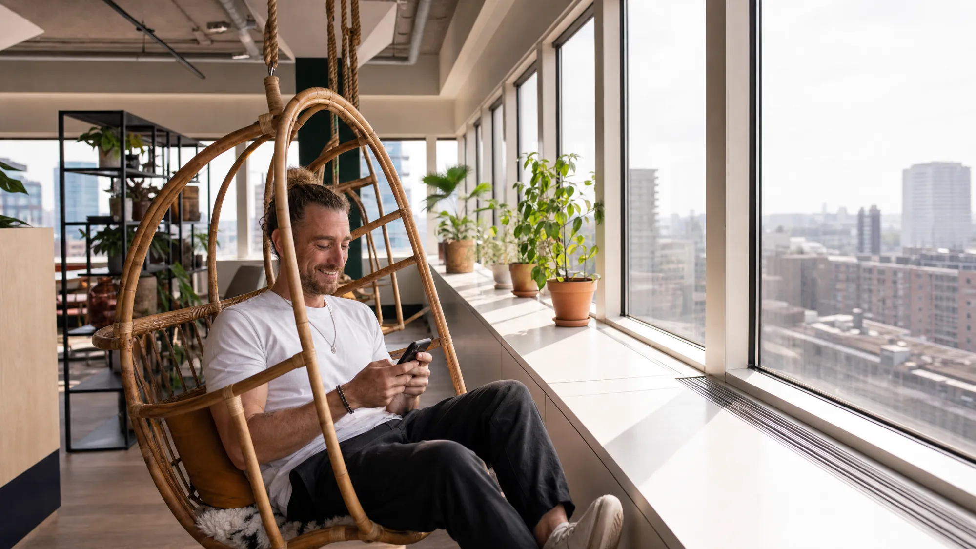 A What's Next team member relaxing with their phone at the studio overlooking the city